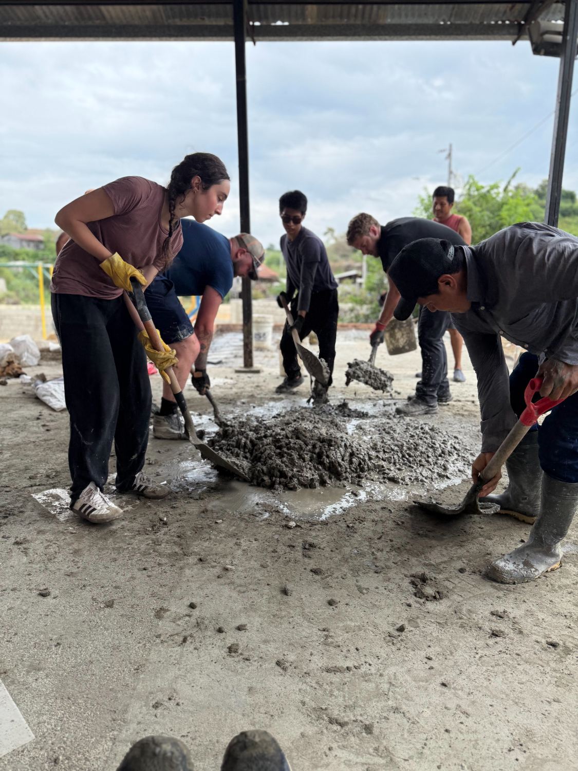Misioneros y vecinos mezclando concreto en la obra