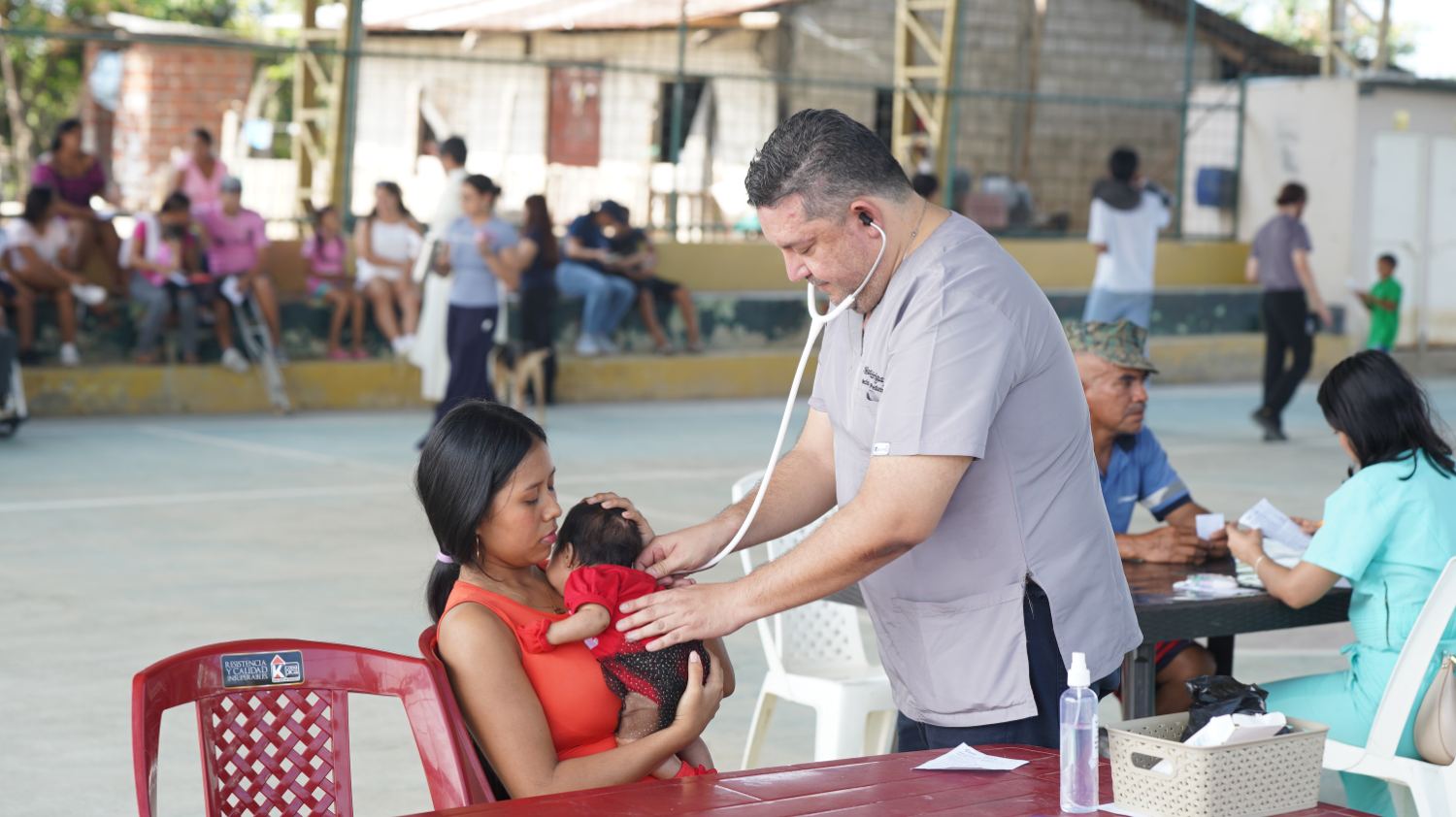 Pediatra auscultando a un bebé en brazos de su madre durante la brigada