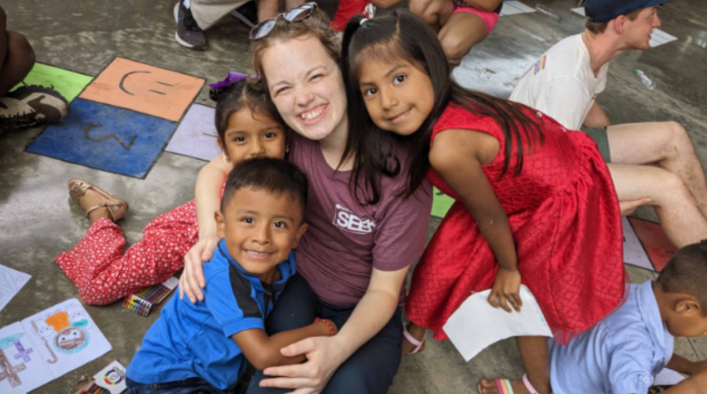 Misionera abrazando a tres niños de la comunidad durante una actividad