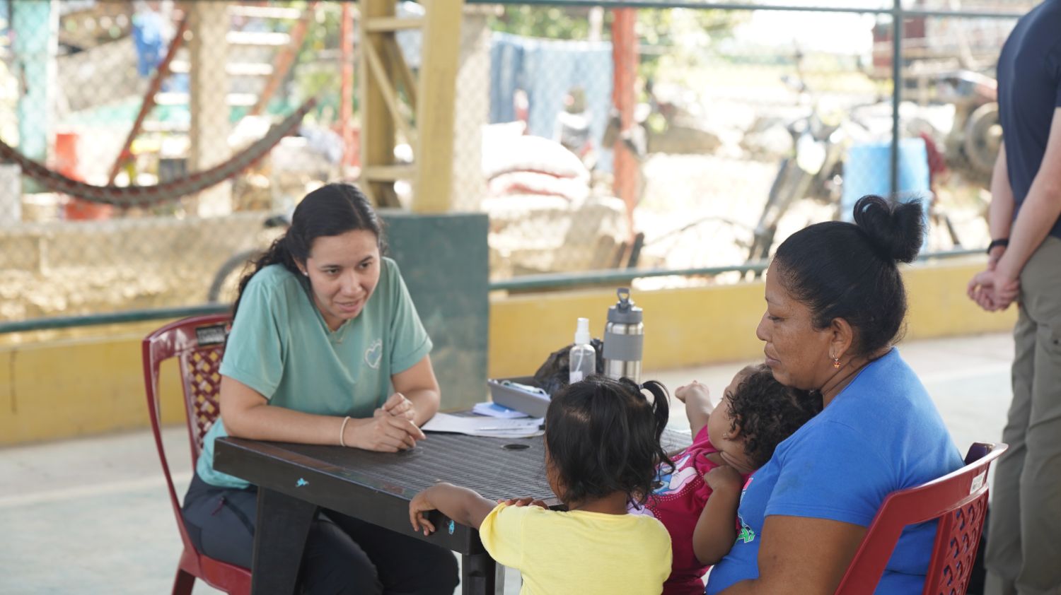 Médica voluntaria conversando con una madre y sus hijas durante la consulta gratuita