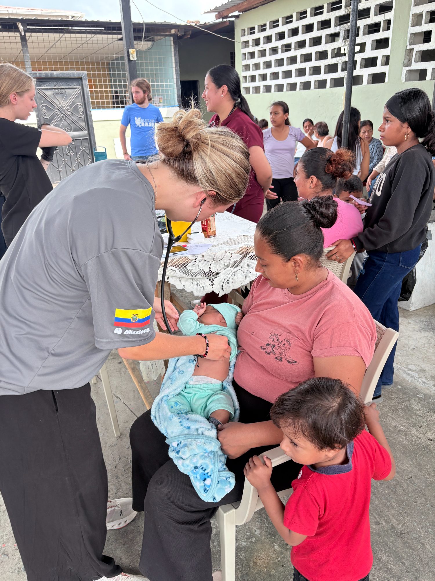 Voluntaria auscultando a un recién nacido en brazos de su madre durante una brigada médica