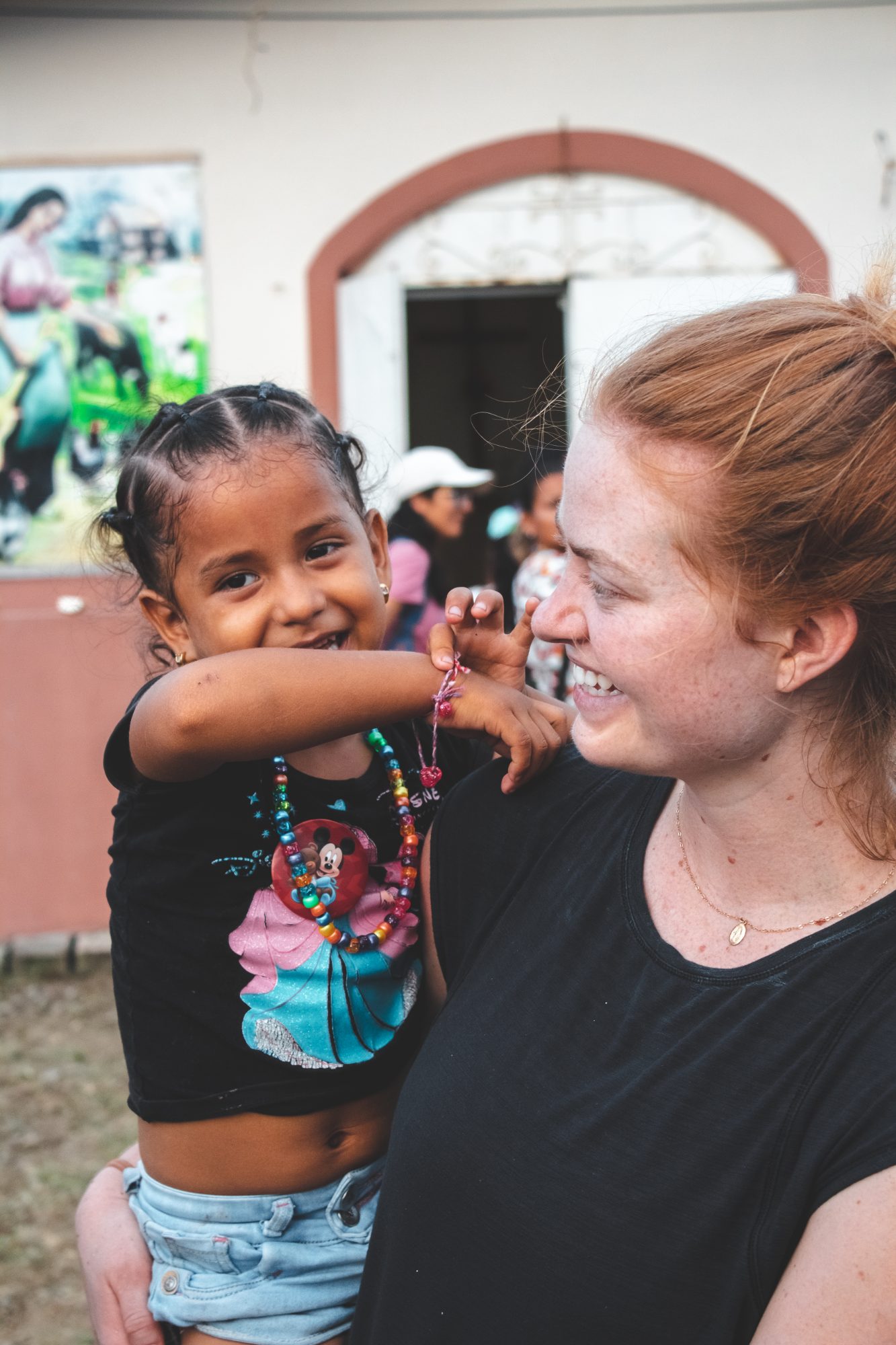Voluntaria y niña de la comunidad riendo juntas durante una misión