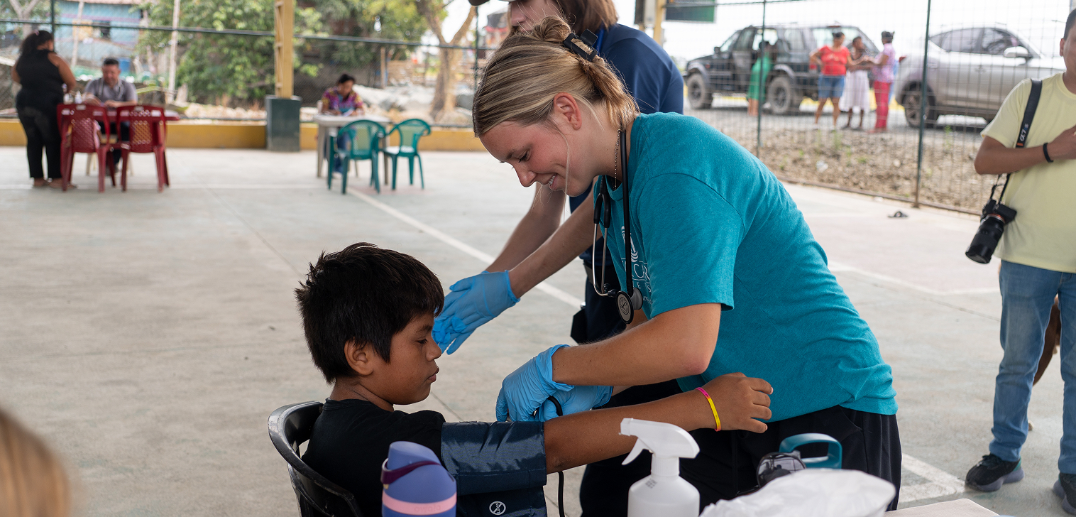 Voluntaria tomando la presión a un niño durante una brigada médica